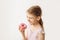 Cute blonde little girl eating pink donut and smiling. Junk food concept