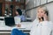 Cute blonde secretary in white blouse talking on phone and writing data in notebook. Indoor portrait of long-haired