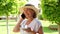 cute blonde senora woman, 50-55 years old, in a hat and a white dress, talks using a smartphone and holds a cup of