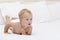 Cute blonde toddler with open mouth in a diaper lying on the white blanket and looking aside. Copy space