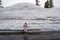 Cute blonde tourist woman poses and stands next to a large mound of plowed snow in Lassen National Park California during summer