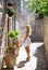 Cute Blonde tourist woman in white dress walking along the small