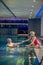 Cute blonde woman in red swimming suit giving hand to her husband in na swimming pool