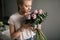Cute blonde young woman wearing fashion clothes sniffs bouquet of flowers