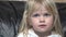 Cute blue-eyed little girl with blond hair looks, talks, wipes her lips, portrait