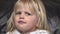 Cute blue-eyed little girl with blond hair make faces, grimacing