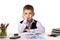Cute bored pupil sitting at the desk with hand under the chin surrounded with stationery