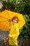 The cute boy of 8-9 years under a yellow umbrella.