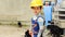 Cute boy as a worker stands near a tractor