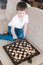 A cute boy of Caucasian appearance plays chess. Games for the development of logic and strategy. Chess tournaments