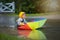 Cute boy with colorful rainbow umbrella on a rainy day, having f