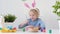 Cute boy coloring eggs for Easter holiday. Preparing for the holiday is a joy for kids.