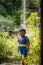 A cute boy dressed as superman showers in the garden