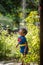 A cute boy dressed as superman showers in the garden