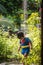 A cute boy dressed as superman showers in the garden