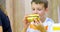 Cute boy eating large hamburger at fast food restaurant. Unhealthy meal for kids. Junk food. Overweight problem child