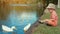 Cute boy feeding water birds in the pond slow motion