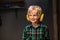 Cute boy with headphones and safety glasses in a carpenter`s workshop, portrait.