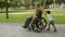 Cute boy helping disabled military dad to wheel heavy wheelchair