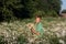 Cute boy holding bouquet of fields camomile flowers in summer day. Back view. Holiday concept