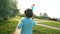 Cute boy holding toy wind turbine in hand, running at sunset summer park. Happy kid, child playing, having fun wiht