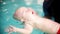 Cute boy learns to swim underwater in swimming pool. Baby swimming underwater with open eys. Healthy family lifestyle