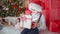 cute boy opens Christmas gift and mysterious light illuminates his face against background of decorations with Christmas