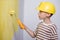 Cute boy with a paint roller. Happy kid helps parents to paint wall. Home renovation