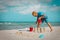 Cute boy play with sand at sea, kid building castle on tropical beach