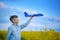 Cute boy plays with a toy airplane in the the blue sky and dreams of travel. Hand with blue toy plane