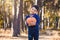 Cute boy with a pumpkin in his hands in a pine forest