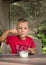 cute boy in a red T-shirt 5 - 6 years old has an appetizing breakfast with yogurt