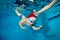 Cute boy in a Santa Claus hat and glasses in a pool underwater. Baby learns to dive. Swimming lessons with a child