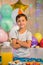 Cute boy standing with arms crossed at birthday party