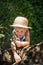 Cute boy with straw hat trying climb on a tree