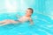 Cute boy swimming in the pool with turquoise water in the summer holidays