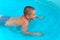 Cute boy swimming in the pool with turquoise water in the summer holidays