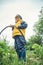 Cute boy takes hose for watering grown plants in garden