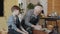 Cute boy talking to senior grandfather in pottery studio making ceramics on throwing wheel