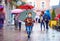 Cute boy with umbrella walking on crowded city street