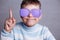 Cute boy in violet sunglasses with opaque lenses pointing upward