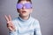 Cute boy in violet sunglasses with opaque lenses showing victory