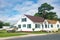 Cute brightly painted white shingled cottage with a boat in the parking lot. coastal town on a sunny day