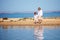 Cute brothers, young kids walking along the lake in shallow water in the summer morning