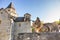 Cute brown cat sitting on wall of ancient castle in Europe. Proud wild cat on sunny day. Pretty kitty in old town. Pets concept.