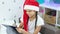 cute brown-haired girl teenager in a red santa hat writes a letter to santa claus sitting on the bed