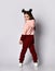 Cute brunette kid girl in modern fashion pink brown hoodie and pants stands back to us looking back over her shoulder