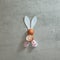 Cute bunny white ears and fluffy white pink paws and egg shells on a gray concrete background. Text space. Top view. Minimal style