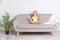 Cute calm little girl meditating in lotus pose with closed eyes sitting on couch at home, child doing mudra gesture