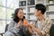 A cute and caring Asian grandson is giving a glass of orange juice to his grandmother